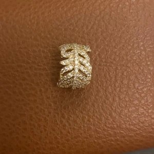 Guldörhänge med lövmönster - Säljer ett elegant guldörhänge med ett detaljerat lövmönster. Perfekt för att ge en touch av naturinspirerad stil till din look. Örhänget är i mycket bra skick och passar både till vardags och festliga tillfällen.