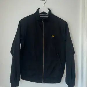 Lyle & Scott Vintage Jacka för sommaren och för dem som är runt 13 år. 44 cm bred i axeln och 68 cm lång från nacken till botten. Innanför jackan är det ett randigt mönster som man ser på bilderna, samt att det finns en ficka. 