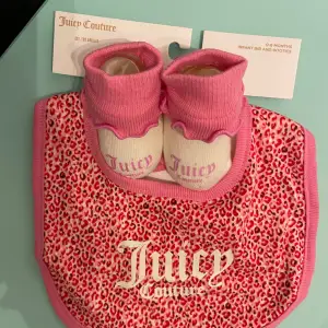 Supersöta rosa och vita babysockor från Juicy Couture. Perfekta för de minsta, med mjukt material och stilren design. Sockorna har en söt rosa kant och vit bas med 'Juicy' tryckt på. Passar perfekt ihop med den matchande haklappen i leopardmönster.