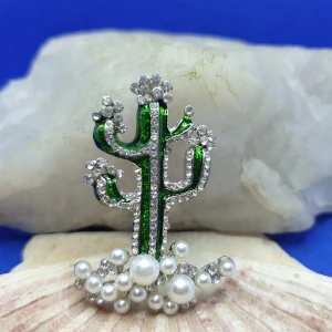 Brosch  - Kaktus med pärlor och kristaller  - En brosch föreställande en Kaktus. Storlek ca 4.5x3cm.  Silverfärgad metall med vacker ytstruktur och emaljering samt kristaller och pärlor