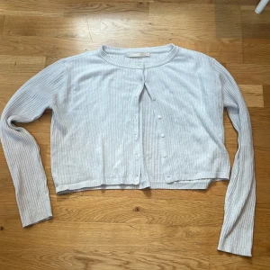 Vit ribbad kofta - Säljer en superfin vit ribbad kofta med knappar framtill. Den har långa ärmar och en croppad passform som gör den perfekt för lager-på-lager-stil. Koftan är i bra skick och passar bra till allt. säljer även en ljusare vit kofta som man knyter. 