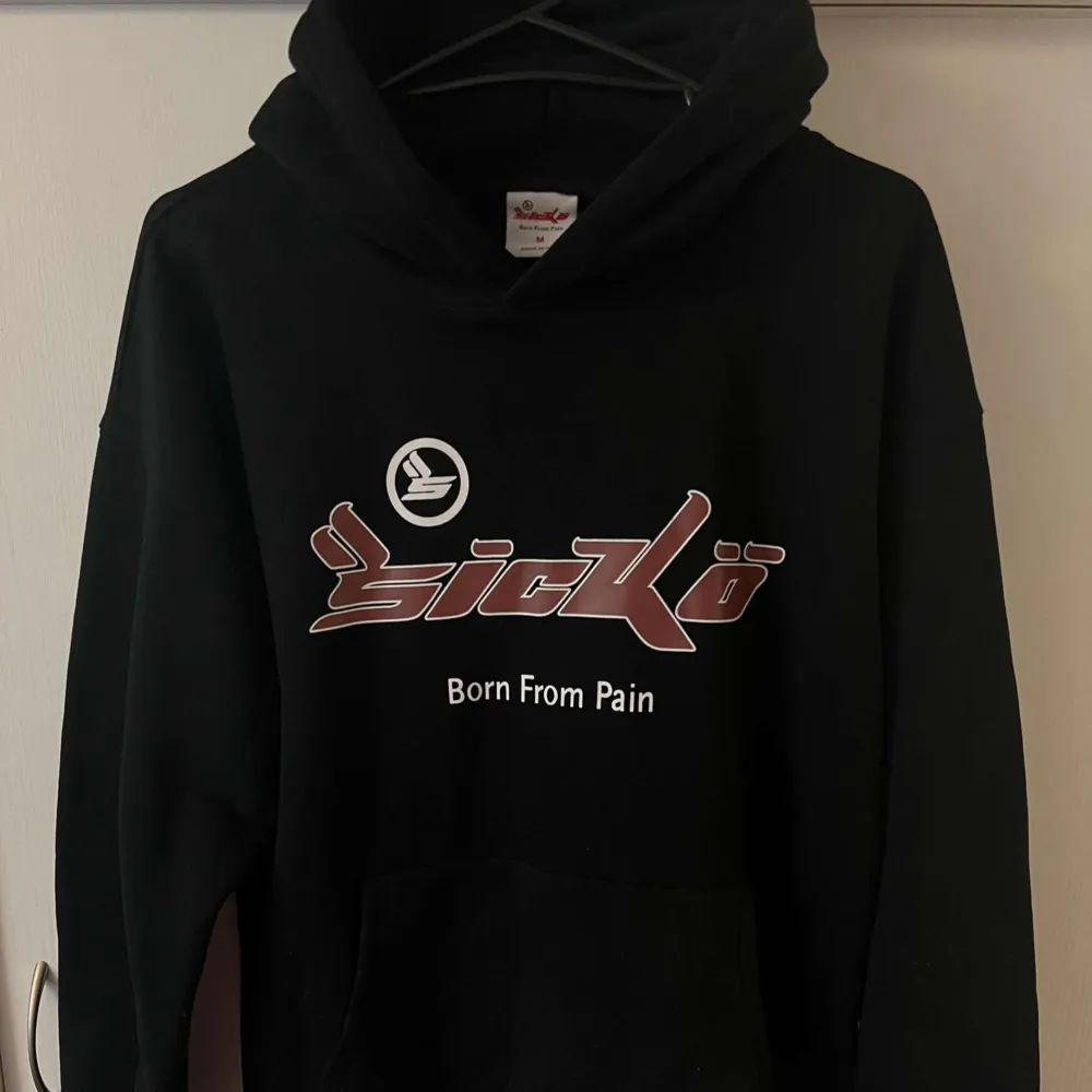 Säljer en svart hoodie från Sickö med texten 'Born From Pain' tryckt på framsidan. Den har en klassisk passform med långa ärmar och en stor ficka framtill. Perfekt för höst och vinter när du vill hålla dig varm och bekväm. 🖤. Hoodies.