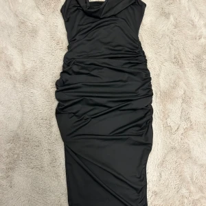 Svart klänning med slits - Svart klänning med rysch på bägge sidor och slits! Är lös vid bysten vilket gör den sjukt snygg och man får fina former🤩🩷