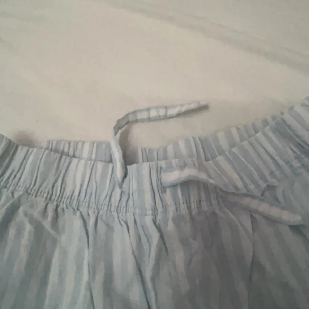 Säljer ett par ljusblå och vita randiga byxor från H&M. De har en bekväm elastisk midja med snörning för justerbar passform. Perfekta för en avslappnad stil! Inprincip oanvända.. Farkut & Housut.