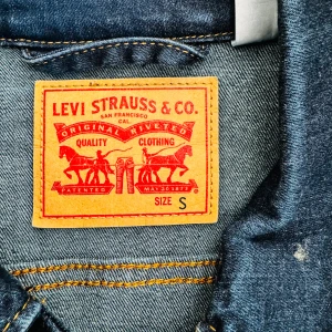Blå jeansjacka från Levi Strauss & Co. - Säljer en snygg blå jeansjacka från Levi Strauss & Co. i storlek S. Jackan har en klassisk design med knappar framtill och två bröstfickor med knappstängning. Perfekt för vår och höst! 🧥💙