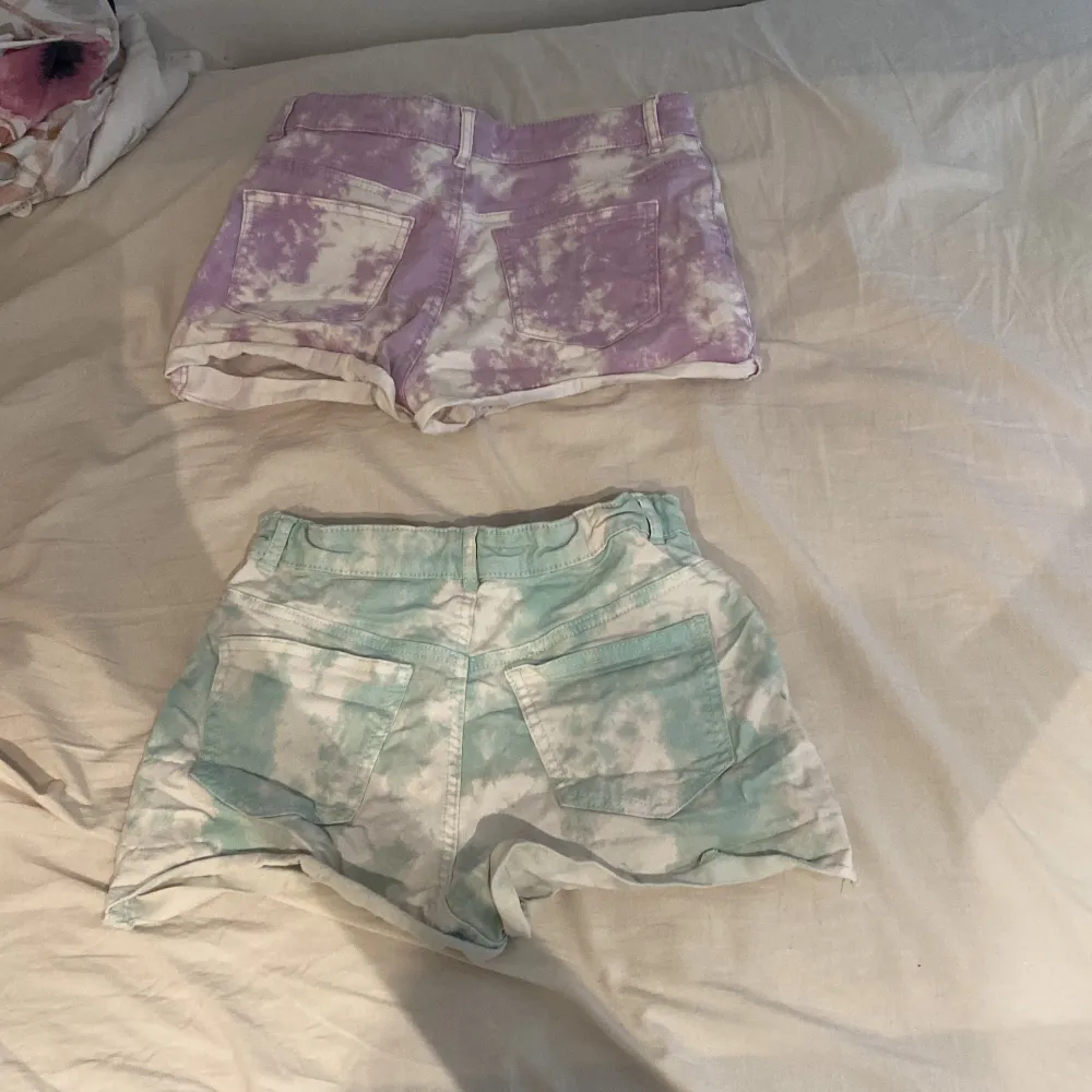 Säljer två par supercoola tie-dye shorts från H&M. Ett par är lila och vitt, och det andra paret är grönt och vitt. Båda har en knapp och dragkedja framtill, samt fickor både fram och bak. Perfekta för sommaren och riktigt sköna att ha på sig. De lila är i storlek 164 och de gröna i 170. Båda kostar 20 men kan säljas enskild för 10 kr/st. Shorts.