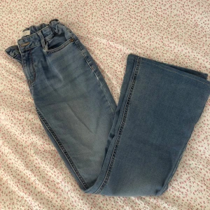Lågmidjade flare jeans - Lågmidjade flare jeans från Lindex kids i storlek 170. Ganska använda. Sydda längst ner för att anpassa min längd (160). På ena benet har jeansen slitits (se bild) men ser ganska bra ut ändå. Annars är jeansen inte så slitna.
