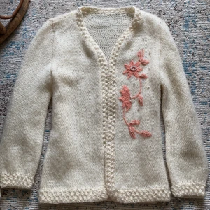 Vit stickad kofta med blommig broderi - Säljer en superfin vit stickad kofta med vackra rosa blommor broderade på framsidan med små pärlor. Den är i nyskick🤍