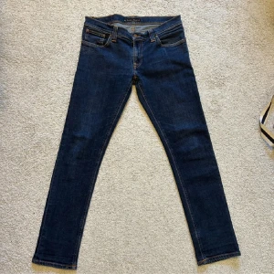 Mörkblå jeans från Nudie Jeans - Säljer ett par mörkblå jeans från Nudie Jeans i storlek 32/30. De är i bra skick och inga slitningar andledningen till att jag säljer är för jag växt ur dom