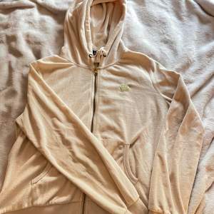 Beige/vit velour zip up tröja med guld text  Färgen är inte exakt som på bilden‼️ Defekter: Finns liten fläck under vänstra armen som på 3:de bilden