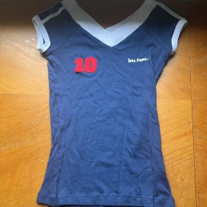Blå topp med vita detaljer och nummer 10 - Säljer en iets frans topp. Den är i bra skick och bara använd 2 gånger.