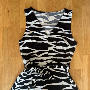 Zebramönstrad klänning - Zebramönstrad klänning från H&M med snörning i midjan, aldrig använd