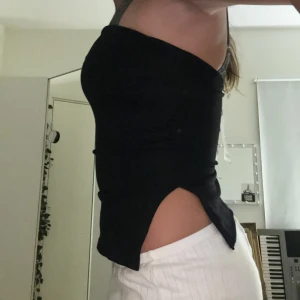 Tubetopp - Typ som kostymbyxor fast i tupetopps format. Den är helt svart med två stycken slittar på sidorna. Helt oanvänd med prislapp kvar. 