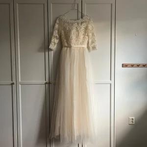 Bröllopsklänning / Brudklänning - Vacker brudklänning i skimrande tyg, med spets och tyll. Ca strl 34. Har inte använt, köpte av en annan privatperson. Väldigt fint skick!