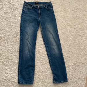 Blå jeans från Vero Moda - Säljer ett par snygga blå jeans från Vero Moda i storlek 32/32 De har en klassisk straight fit och är tillverkade i slitstarkt denim. Perfekta för både vardag och fest! 🥳Tyvärr en reva bak. Se bild. 