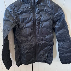 Peak performance - Helium down-jacka från peak storlek xs, dam. Begagnat skick, har en liten lagning vid vänstra fickan som syns på bilden, annars hel.