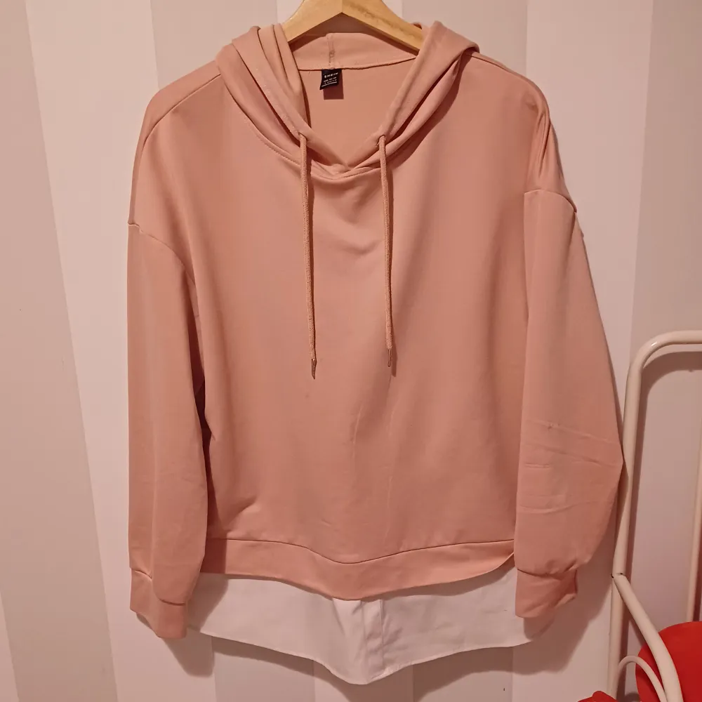 Säljer en superfin beige hoodie med en cool vit detalj längst ner. Den har en skön luva och långa ärmar, perfekt för en avslappnad stil. Materialet känns mjukt och bekvämt, perfekt för höst och vår. Passar perfekt till jeans eller leggings!. Tröjor & Koftor.