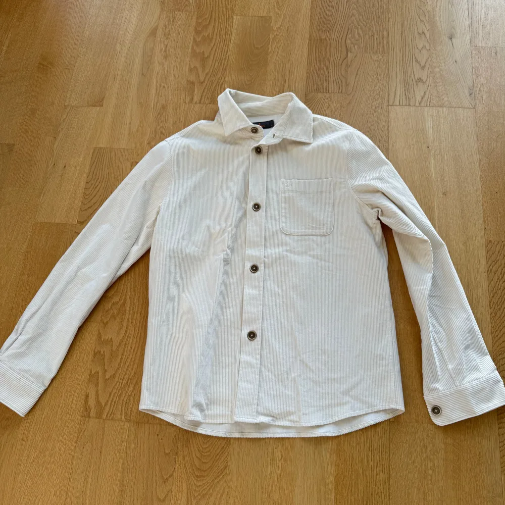 Säljer en stilren krämvit overshirt från Morris. Skjortan har en klassisk krage och en bröstficka med en liten broderad detalj.  Väldigt bra skick, knappt använd. Pris kan diskuteras hör av dig vid frågor.. Skjortor.