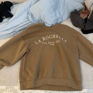 Beige sweatshirt från La Rochelle - Säljer en snygg beige sweatshirt från Gina tricot. Tröjan har en avslappnad passform och långa ärmar, perfekt för en chill dag eller en casual utflykt. Den är i bra skick och superbekväm!