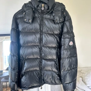 Moncler Maya Strl 3 - Moncler dun jacka storlek 3 (M/L)  I använt skick. Hål på baksidan finns (se bild , sydd)  Hål i fickan finns och det går att sy enkelt.
