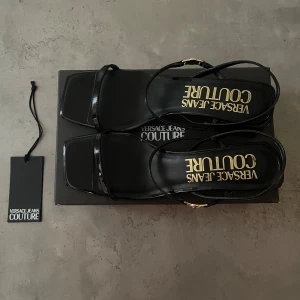 Slingbacks Versace - Köpta för 2 år sedan, bara använt 1 gång. Nypris 2000kr. Sitter bra på foten hela dagen, bekväma att gå, stå och dansa i. Perfekt inför stundentbal och liknande. 