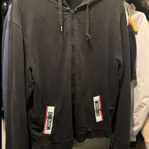 Moschino Hoodie M - Fin Moschino Hoodie i storlek M. Svart med vit/röda detaljer Fint skick.