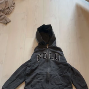 Grå zip hoodie vintage  - Grå zip hoodie vintage. Polo Ralph Lauren. Skick 7/10 pga en bit tyg som lossnat vid ena änden av armen som man ser i sista bilden.