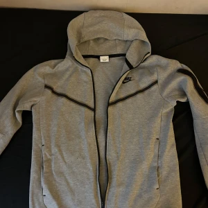 Grå hoodie från Nike - Säljer en grå nike techhoodie i storlek M men det passar även S👍🏽 Perfekt för både träning och vardag. Skick: 8/10, kond: 8/10