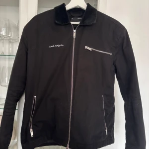 Arigato Jacka - Svart jacka med dragkedja framtill och två fickor med dragkedja på sidorna. Jackan har en liten ficka med dragkedja på bröstet. Jackan har en mjuk krage i sammet. Orginalpris 3000. Inga defekter eller så Con 8/10