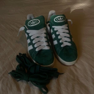 Adidas Campus 00s - Bestämt mig att sälja mina gröna adidas campus 00. Som ni ser på bilden så har jag laceat om dem men inte använt skorna utomhus. Köptes under sommaren 2024 på Size? Skostorlek: 47 1/3 Nypris: 1300kr