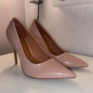 Slutsålda. Beige med rosa underton. Penelope Stiletto Pumps in Beige Patent. Gummiband vid häl för extra stöd. Klackens höjd: 9,5 cm. Stl: 36. Skick: Nyskick - Oanvända. Nypris: 480 kr 