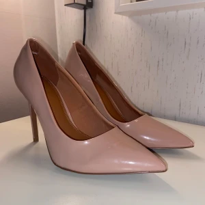 Beige Stiletto Pumps från ASOS Design  - Slutsålda. Beige med rosa underton. Penelope Stiletto Pumps in Beige Patent. Gummiband vid häl för extra stöd. Klackens höjd: 9,5 cm. Stl: 36. Skick: Nyskick - Oanvända. Nypris: 480 kr 