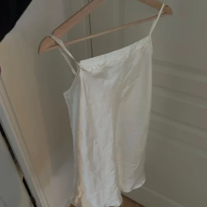 Vitt nattlinne - Säljer ett vitt vintage nattlinne i glansigt tyg. Har några mindre defekter. Justerbara axelband. 