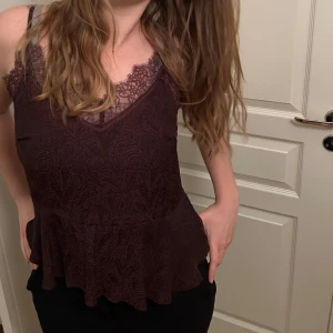 Vinrött mönstrat spetslinne - Säljer ett superfint vinrött linne med spetsdetaljer och volang. Det har smala axelband och en vacker spetskant vid halsringningen. Mönstret 🥺