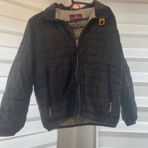 Svart quiltad jacka från Parajumpers - Säljer en svart quiltad jacka från Parajumpers i mycket bra skick. Jackan har en dragkedja framtill och två praktiska fickor med dragkedjor. Perfekt för höst och vår, med en stilren look och bekväm passform. Passar både till vardags och lite finare tillfällen. Köpt för 3000kr