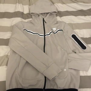 Grå nike tech  - Säljer en grå hoodie från Nike i mycket bra skick. Perfekt för höst och vår, med en normal passform och långärmade ärmar. Den är perfekt för både träning och vardag.