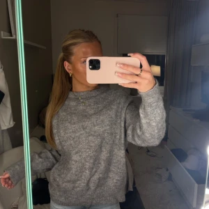 Grå stickad tröja - Mysig grå stickad tröja i mycket bra skick. Perfekt för höst och vinter med sin varma och bekväma design. Tröjan har långa ärmar och en normal passform, vilket gör den idealisk för vardagsbruk. Ett måste i garderoben för kyliga dagar! 