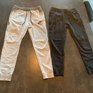 Nike mjukisbyxor i svart och vit - Säljer två par Nike mjukisbyxor i storlek S. Ett par är vita och det andra är svarta. Båda har elastisk midja med snörning och muddar vid bensluten. Perfekta för en avslappnad stil eller träning. De är i bra skick och superbekväma! 1 för 150 båda för 300