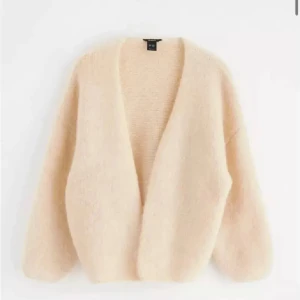 Beige fluffig kofta från H&M - Supermysig beige kofta från H&M i fluffigt material. Perfekt för kyliga dagar när du vill ha något bekvämt och stilrent. Den har en öppen design utan knappar och är i en lös passform. Passar perfekt till både vardag och mysiga hemmakvällar.