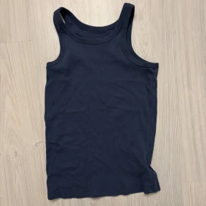 Mörkblå ribbad tanktop från lager 157 - Säljer en mörkblå ribbad tanktop från 157 i storlek S. Toppen är ärmlös och tillverkad i 100% bomull, vilket gör den superbekväm och perfekt för sommardagar. Den har en klassisk design som passar till det mesta. Perfekt för både vardag och fest! 💙