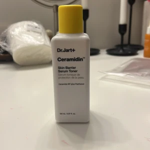 Dr.Jart+ Ceramidin Skin Barrier Serum Toner - Säljer en Dr.Jart+ Ceramidin Skin Barrier Serum Toner. Denna toner är perfekt för att stärka hudbarriären och innehåller ceramide NP plus panthenol. Flaskan är vit med en gul kork och innehåller 150 ml. Perfekt för att återfukta och skydda huden efter rengöring.