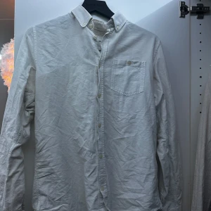 Vit skjorta från Norse Projects - Säljer en stilren vit skjorta från Norse Projects i storlek M. Skjortan har en klassisk design med knappar och en bröstficka. Perfekt för både vardag och festliga tillfällen. Den är i bra skick och passar till många olika outfits.