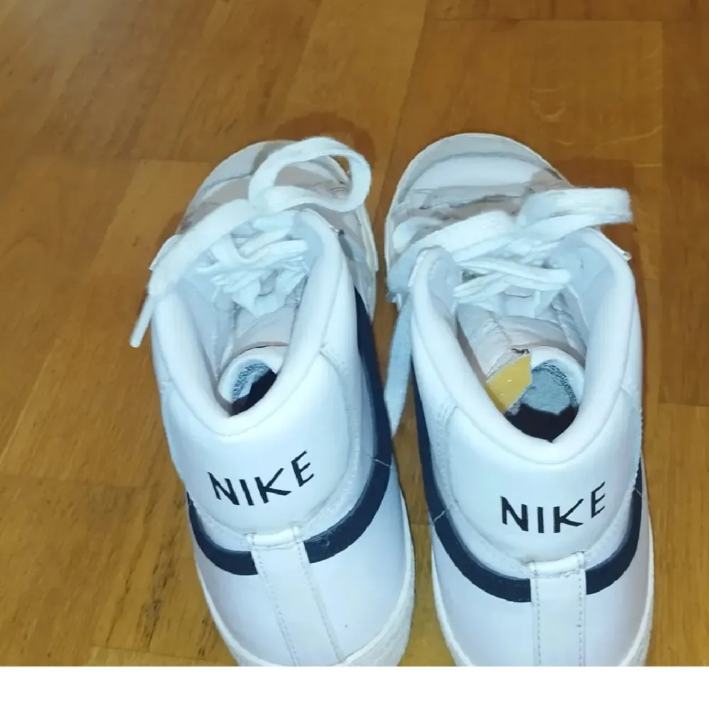 Ett par vita Nike blazers med svart nike märke. Den är sparsam använd med väldigt få användningar. . Kengät.