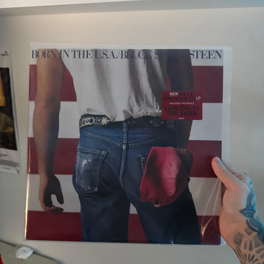 Det här är ett ikoniskt album av Bruce Springsteen, 'Born in the USA'. Omslaget visar en person i jeans med en röd keps i bakfickan, mot en bakgrund av den amerikanska flaggan. Perfekt för samlare eller fans av klassisk rockmusik.. Böcker.