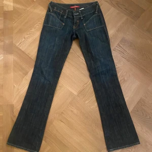 Mörkblå jeans från Guess - Säljer ett par snygga mörkblå jeans från Guess. De har en cool ficksdesign och snygga detaljer baktill. Jeansen är bootcut och low waist 😍😍