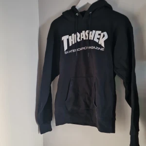 Svart Thrasher hoodie - Säljer en svart Thrasher hoodie i storlek S i mycket bra skick. Den har en stor vit logga på framsidan och en klassisk känguruficka. Perfekt för skate eller chill dagar. Huvan har dragsnören och tröjan är superbekväm. 
