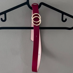 Rött bälte med gulddetaljer från H&M - Säljer ett snyggt rött bälte från H&M i storlek S. Bältet har en stilren design med två guldfärgade ringar som spänne. Perfekt för att piffa upp en outfit till festen eller sommarens äventyr. Använd ett fåtal gånger, så det är i bra skick. Passar perfekt till både jeans och klänning!