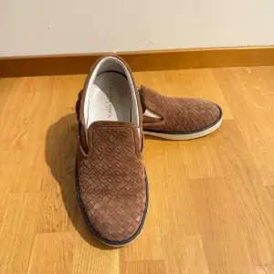 Säljer ett par snygga bruna loafers från Bottega Veneta i mycket bra skick. De är gjorda i ett flätat mönster av mocka och har en vit sula. Perfekta för både vardag och fest! Storlek och passform är normal. Passar perfekt till nästan alla årstider! Priset kan diskuteras vid snabb affär och byten kan vara intressant!