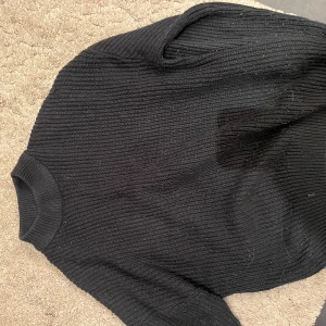 Svart stickad tröja - Säljer en svart stickad tröja i bra skick. Den är perfekt för kyliga dagar och har en klassisk design med rund hals och långa ärmar. Passar till både vardag och lite finare tillfällen. Supermysig och stilren!