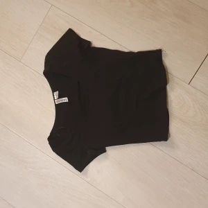 Svart topp från H&M Divided - Säljer en enkel och stilren svart topp från H&M Divided i storlek XXS. Toppen har en tight passform och kortärmad. Säljer eftersom den är för liten❤️❤️ Skriv för fler bilder/ frågor!